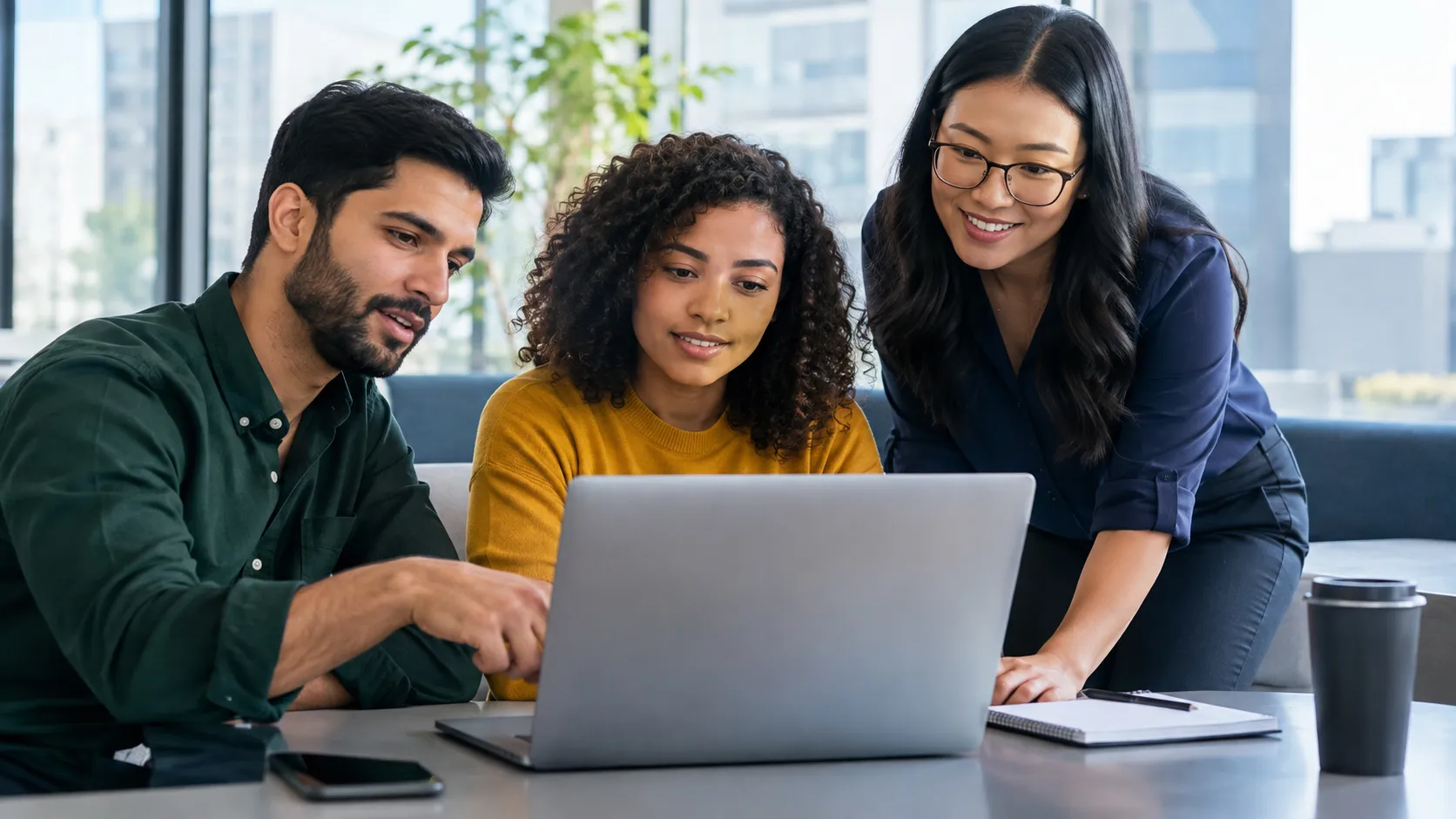 Three coworkers collaborate around a laptop in a modern workspace, sharing information and reviewing content together to support effective business communication, teamwork, and informed decision-making.